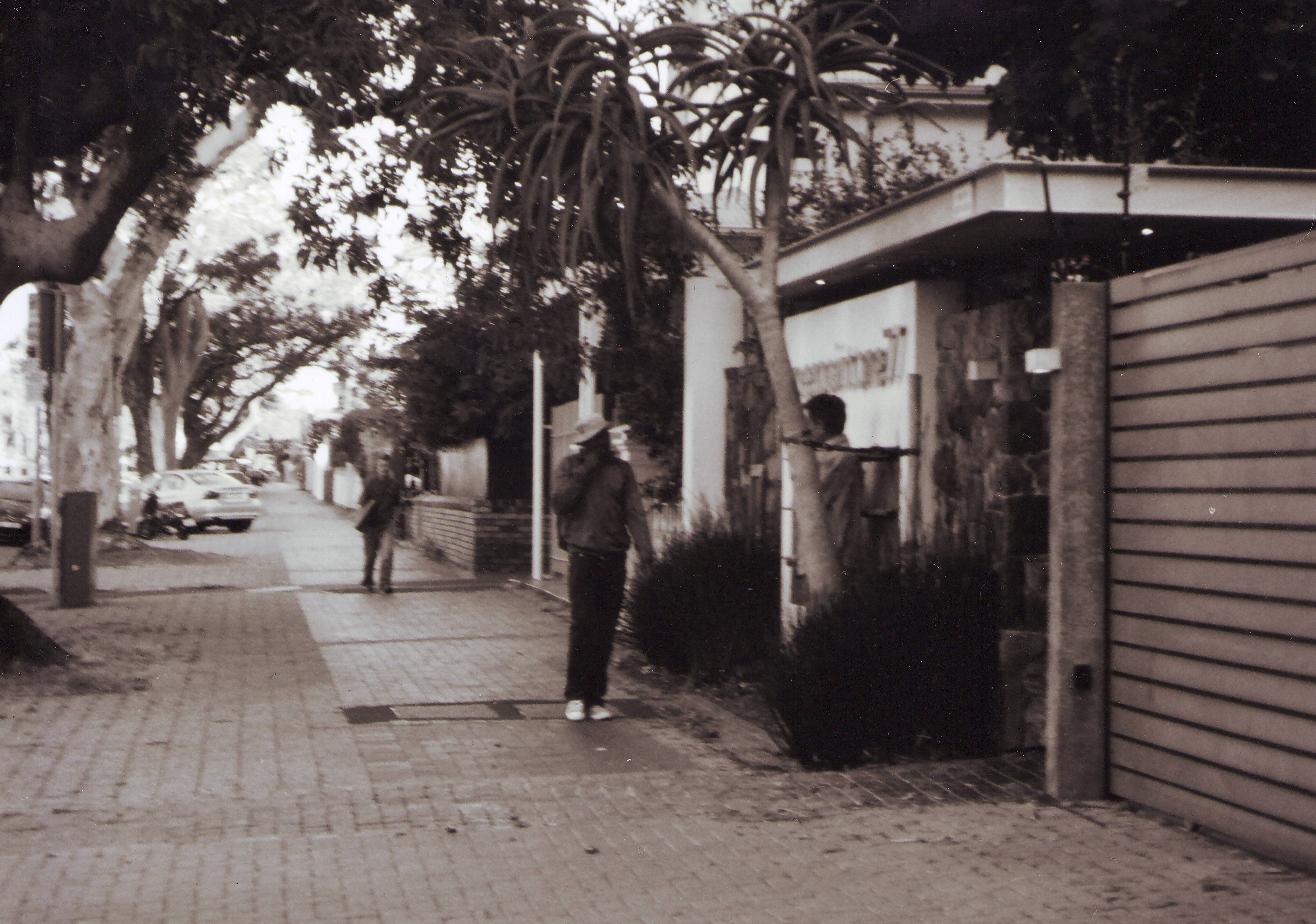 Verwischtes schwarz-weiss-Foto: Zwei Menschen laufen über einen Gehweg in Kapstadt. 