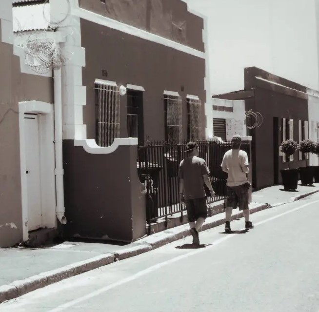 Zwei Menschen laufen entlang einer Häuserreihe durch Kapstadt.